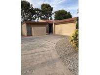 Tan single story home with mature trees, desert landscaping, and a two car garage at 150 W Tam Oshanter Dr, Phoenix, AZ 85023