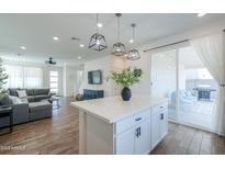 Modern kitchen with a center island, white cabinets, pendant lighting, and open access to the living room at 1901 W 23Rd Ave, Apache Junction, AZ 85120