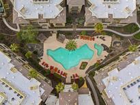 Aerial view of a condo community pool with lounge seating, mature landscaping, and a rock water feature at 7601 E Indian Bend Rd # 1017, Scottsdale, AZ 85250