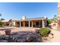 Spacious backyard featuring a covered patio, mature landscaping, and desert surroundings at 15479 W Whitton Ave, Goodyear, AZ 85395