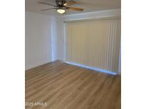 Bright living room featuring wood floors, a ceiling fan, and sliding door with vertical blinds at 17017 N 12Th St # 1135, Phoenix, AZ 85022