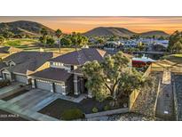 Stunning two-story home boasts lush landscaping, mature trees, and a charming water feature against a picturesque mountain backdrop at 21915 N 65Th Ave, Glendale, AZ 85310