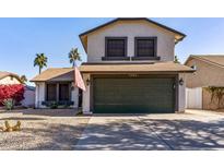 Charming two-story home featuring a spacious driveway, a green garage door, and desert landscaping at 24021 N 39Th Ln, Glendale, AZ 85310