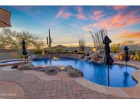 Inviting pool features a rock waterfall and spillover spa surrounded by lush landscaping at 8320 E Arroyo Hondo Rd, Scottsdale, AZ 85266
