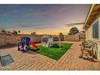 Lovely backyard featuring a brick patio, artificial grass, and play area for children at 10733 W Seldon Ln, Peoria, AZ 85345