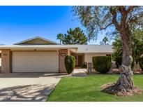Charming single-Gathering home with a lush green lawn, mature trees, and a welcoming two-car garage at 12633 W Brandywine Dr, Sun City West, AZ 85375