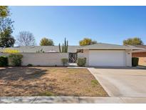 Charming single-story home featuring a brick wall, gate, desert landscaping, and a two-car garage at 18614 N Conestoga Dr, Sun City, AZ 85373