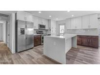 Bright kitchen features white cabinetry, stainless steel appliances, and spacious island with quartz countertops at 2447 E La Jolla Dr, Tempe, AZ 85282