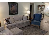 Cozy living room featuring a plush sofa, blue armchair, area rug, and stylish decor at 459 S Boojum Way, Mesa, AZ 85208