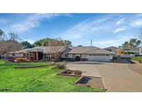 Charming single-story home boasts a lush green lawn and mature landscaping, perfect for curb appeal at 5335 E Exeter Blvd, Phoenix, AZ 85018