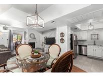 Bright dining area with a glass table, rattan chairs, and a modern light fixture, open to living room and kitchen at 1211 N Miller Rd # 258, Scottsdale, AZ 85257