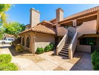 Two-story condo with a red tile roof and private entrance, accented by manicured landscaping and clear blue skies at 1211 N Miller Rd # 258, Scottsdale, AZ 85257