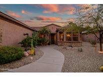 Well-manicured home featuring desert landscaping with cacti, palm trees and a stone pathway to the front door at 15131 W Daybreak Dr, Surprise, AZ 85374