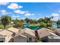 Aerial view showcasing a well-maintained home, lush landscaping, golf course, and serene lake views at 17077 N Zuni Trl, Surprise, AZ 85374