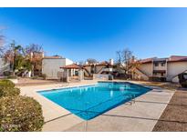 Community pool area features clear blue water, a gazebo, and nearby condominium buildings under a clear sky at 16402 N 31St St # 102, Phoenix, AZ 85032