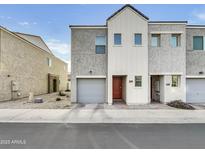 View of townhome with gray stucco, white trim, brown door, garage, and rock landscaping at 2181 W Harmont Dr, Phoenix, AZ 85021