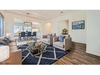 Open-concept living room featuring stylish furniture, a modern rug, and seamless flow to the dining area at 2730 W Via Calabria St, Phoenix, AZ 85086