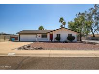 Charming single-story home featuring a two-car garage, red front door, and a well-manicured front yard at 2801 E Sylvia St, Phoenix, AZ 85032