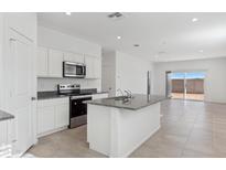 Bright kitchen features white cabinets, stainless steel appliances and an island with granite counters at 1432 W Hess Ave, Coolidge, AZ 85128