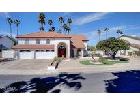 Stunning two-story home with red tile roof, white facade, three-car garage and palm trees at 2542 S Playa --, Mesa, AZ 85202