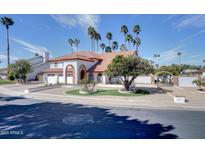 Inviting two-story home featuring a red tile roof, white stucco walls, and lush desert landscaping with mature palm trees at 2542 S Playa --, Mesa, AZ 85202