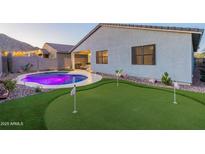 This backyard features a pool, putting green and desert landscaping for a relaxing outdoor experience at 4593 W Bush Bean Way, San Tan Valley, AZ 85144