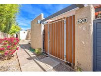 Charming gated entry with flowering shrub, desert landscaping and clear blue sky at 620 S Allred Dr, Tempe, AZ 85288