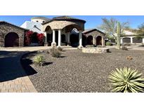 Stunning home exterior with stone accents, desert landscaping, and a circular driveway creates an inviting curb appeal at 8214 E Kael St, Mesa, AZ 85207