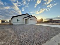 New single-story home featuring a low-maintenance gravel yard and a long driveway leading to an attached two-car garage at 8477 W Tinajas Dr, Arizona City, AZ 85123