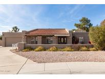 Charming single-story home featuring a red tile roof, low rock landscaping, and front porch at 8544 E San Lorenzo Dr, Scottsdale, AZ 85258