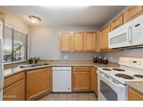 Kitchen with wooden cabinets, white appliances and a double stainless steel sink at 10115 E Mountain View Rd # 1119, Scottsdale, AZ 85258
