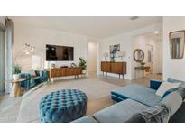 Bright living room showcasing a modern TV wall, light wood furnishings, and stylish blue furniture at 18501 W Galveston St, Goodyear, AZ 85338