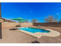 Backyard swimming pool in a gravel yard featuring lounging chairs and patio umbrellas at 19259 N Ventana Ln, Maricopa, AZ 85138