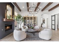 Bright living room featuring a fireplace, wood beams, modern chandelier, and stylish decor at 21432 N 77Th Pl, Scottsdale, AZ 85255