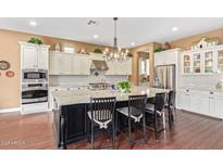 Bright kitchen showcasing white cabinets, stainless appliances, and a large center island with barstool seating at 3881 E Birchwood Pl, Chandler, AZ 85249