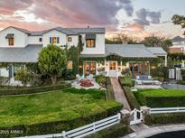 Stunning two-story white home with lush landscaping, a manicured lawn and charming brick pathway at 4716 N Dromedary Rd, Phoenix, AZ 85018