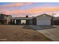 Charming single-story home with a well-manicured lawn and attached two-car garage at 5013 W Orchid Ln, Glendale, AZ 85302