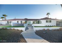 Charming white single-story home featuring a well-manicured landscape, complemented by palm trees and a blue door at 5801 N 22Nd Pl, Phoenix, AZ 85016