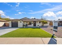 Charming single-story home featuring a well-manicured lawn, attached garage, and inviting front porch at 8215 E Cypress St, Scottsdale, AZ 85257