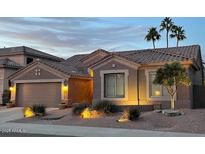 Charming single-story home featuring desert landscaping, a neutral color palette, and well-lit exterior at dusk at 1314 W Windsong Dr, Phoenix, AZ 85045