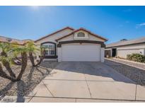 Charming single-story home featuring a two-car garage and desert landscaping with mature palm trees under a clear blue sky at 3043 W Melinda Ln, Phoenix, AZ 85027