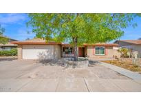 Charming single-story home featuring a brick facade, mature shade tree, and a two-car garage at 5216 W Beryl Ave, Glendale, AZ 85302