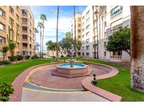 Beautiful courtyard with water fountain, green lawn, and tall trees within a multi-story apartment building at 7830 E Camelback Rd # 108, Scottsdale, AZ 85251