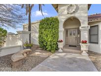 Inviting front entrance with decorative planters and a stone bench, framed by a lush green shrub and stucco walls at 4010 E Grandview St, Mesa, AZ 85205