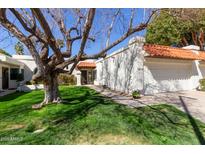 Charming home featuring a red tile roof, lush green lawn, and a mature shade tree at 9210 E Altadena Ave, Scottsdale, AZ 85260