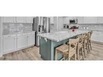 Kitchen island with white granite countertops and seating in a well lit kitchen at 3533 E Harwell Rd, Gilbert, AZ 85234