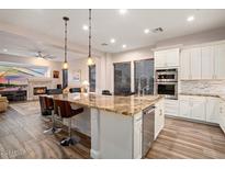 Modern kitchen features granite countertops, stainless steel appliances, island with seating, and an open floor plan at 12663 W Pinnacle Vista Dr, Peoria, AZ 85383
