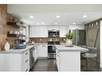 Bright, modern kitchen with white cabinets, stainless steel appliances, concrete countertops, and wood-look backsplash at 6845 E Osborn Rd # D, Scottsdale, AZ 85251