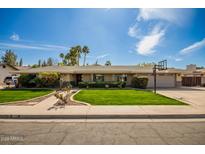 Charming single-story home featuring a well-manicured lawn, mature trees, and a basketball hoop over the garage at 1541 E Hope St, Mesa, AZ 85203