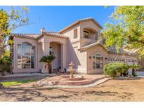 Inviting two-story home featuring a decorative fountain, desert landscaping, and a well-manicured lawn at 1831 W San Angelo St, Gilbert, AZ 85233